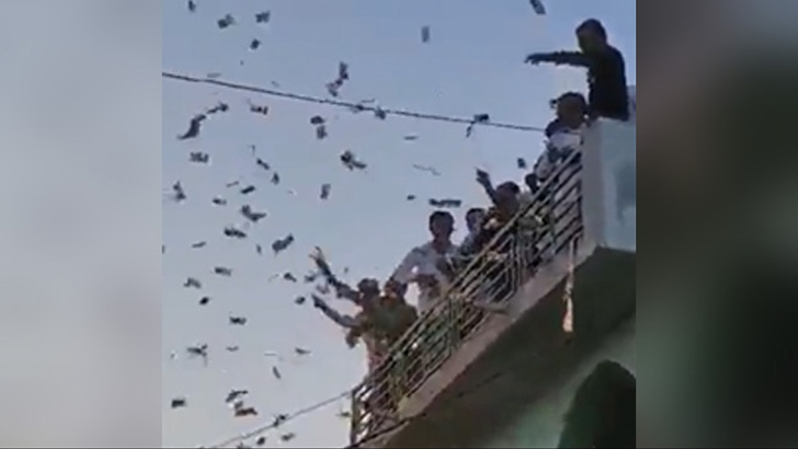 ছাদ থেকে ৫০০ ও ১০০ রুপির নোট উড়াচ্ছেন গ্রামপ্রধান!